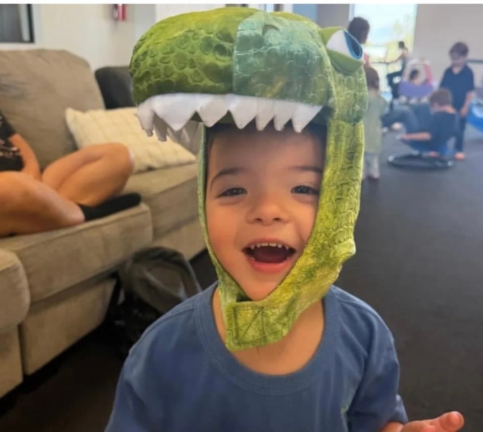 Happy child wearing a dinosaur costume hat at VIP Family Indoor Play